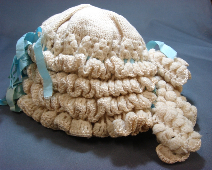 4 Looking a little like a lawyers wig, this knitted baby bonnet was made in 1896..jpg